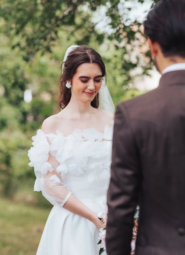 Mariée les yeux fermés lors de la découverte, en robe blanche à fleurs, face à son futur mari.