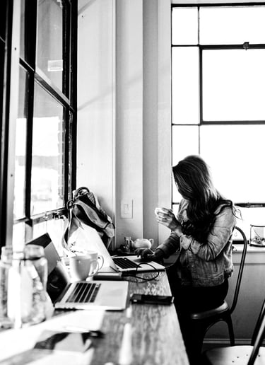 A woman works on a laptop at a cafe