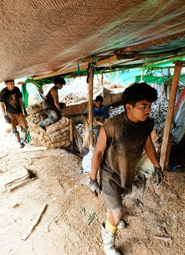 Manual laborers working in an underground mining site with sacks of raw materials.