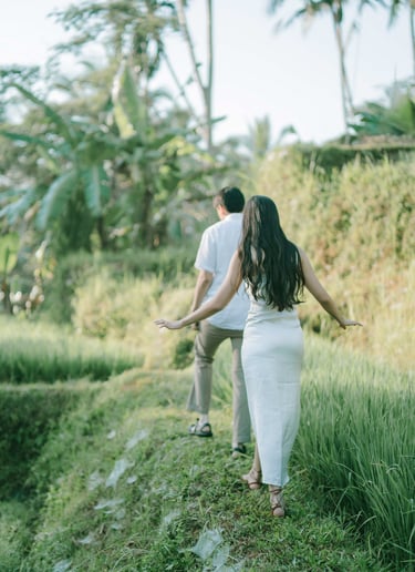 Intimate couple walking along the rice terrace path at sunrise in Tegalalang Ubud Bali.