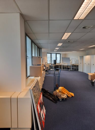 Espace vide avant transformation en bureaux avec de grandes baies vitrées et du mobilier.
