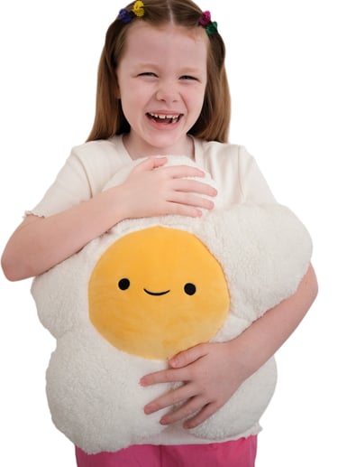 A smiling young girl holding a daisy-shaped plush