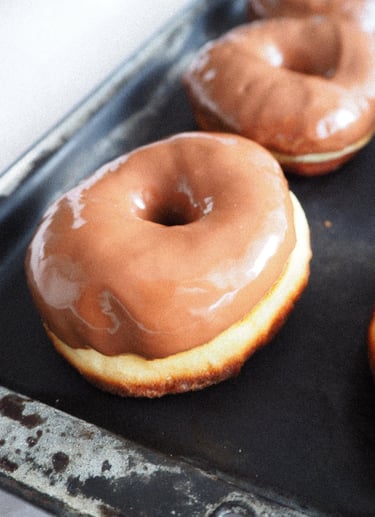 zbliżenie na pączek z dziurką z polewą z mlecznej czekolady