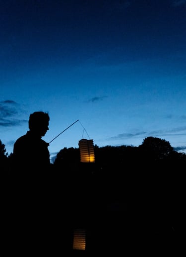 la silhouette d'un homme qui tient une lanterne à la tombée de la nuit