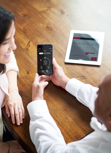 a man and woman sitting at a table with a tablet