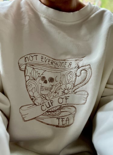 a white sweatshirt with a design thats embroidered saying not everyones cup of tea