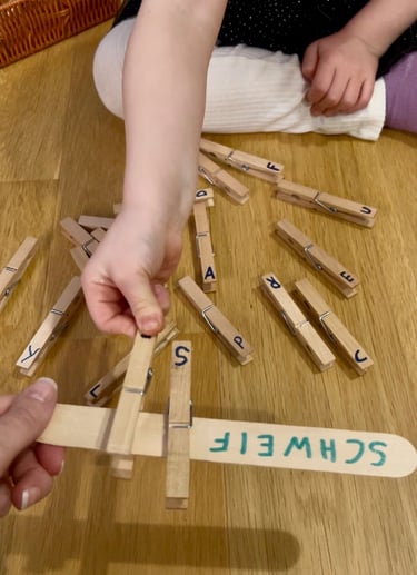 Child matching wooden letter clothespins to a craft stick for a spelling and literacy activity.