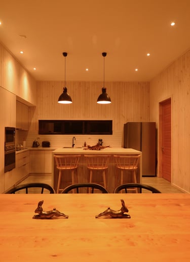 Una cocina con una mesa y sillas y una cocina., luz suspendida en mesa