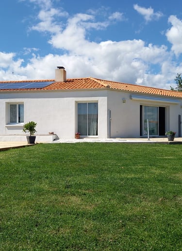 une grande maison blanche avec deux baies vitrées et une fenêtre