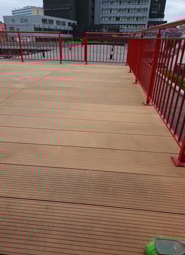 Terrasse extérieure en lames composites installée sur structure rouge métallique, finition propre et