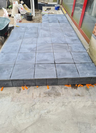 Terrasse surélevée en dalles béton anthracite, installation structurée sur plots réglables.