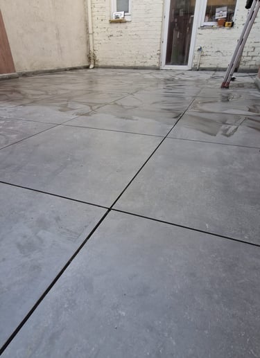 Terrasse extérieure en dalles de béton gris clair posées sur lit de mortier, aspect brut et contempo