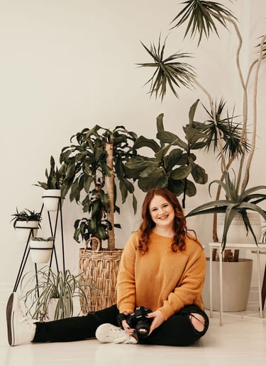 Rachel smiling and sitting in front of indoor plants