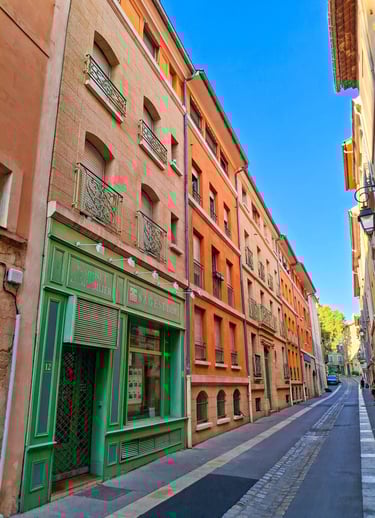 viale di piccola cittadina francese costeggiata da palazzine colorate tipiche della provenza
