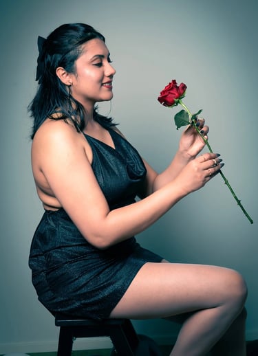 a woman in a black dress sitting on a stool