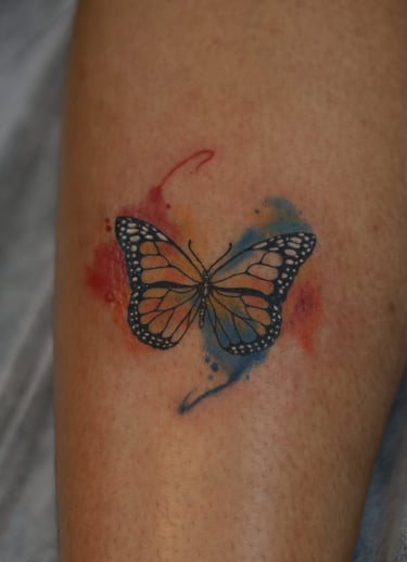 Butterfly tattoo with red and blue watercolor fill on leg by Dudo’s Hyderabad