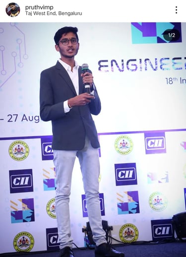 Pruthvi M P in a suit holding a microphone