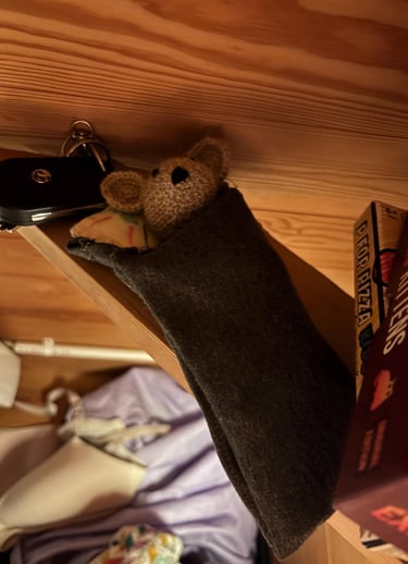 a little crocheted mouse is hanging from a shelf