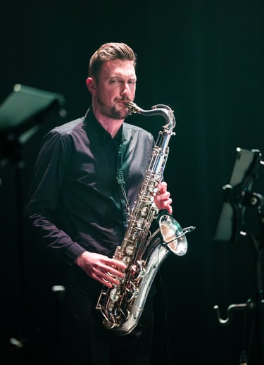 un homme en chemise noire jouant du saxophone