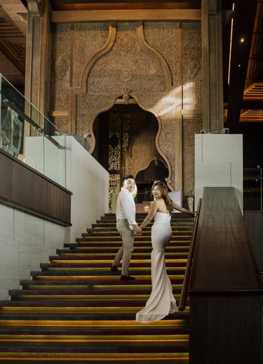 Couple walking down the grand staircase during a luxury prewedding photoshoot at Apurva Kempinski Bali