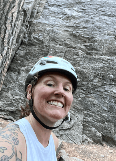 A smiling woman in front of a rock face