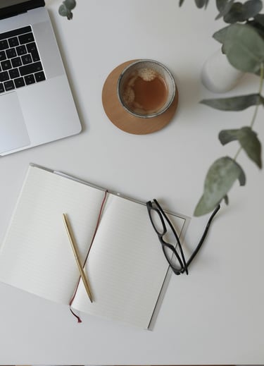 Workspace of a business operations support specialist with a laptop, coffee, and notebook