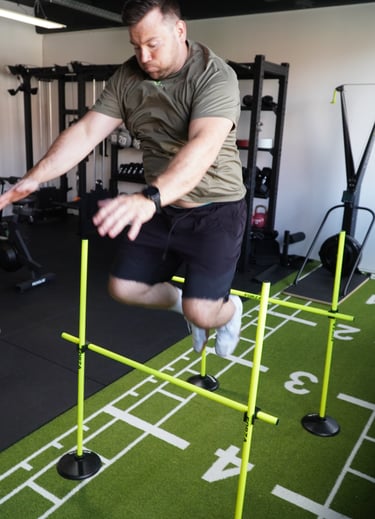 Ein Mann springt über eine Hürde im Fitnessstudio.