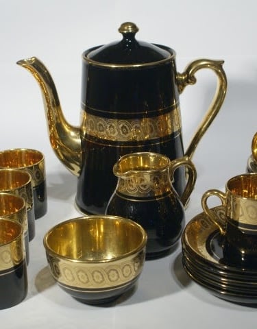 Vintage black and gold porcelain coffee set including a tall pot, creamer, sugar bowl, cups, and saucers.