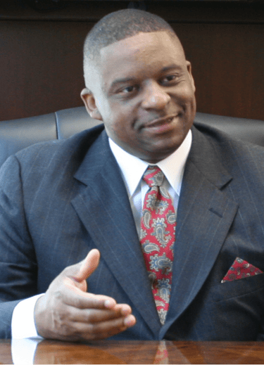Mark T Stewart in a suit and tie sitting at a desk
