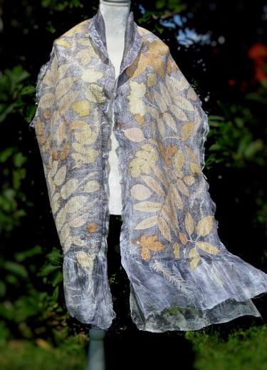 Handmade silk scarf with botanical print leaf patterns on a white mannequin outdoors.