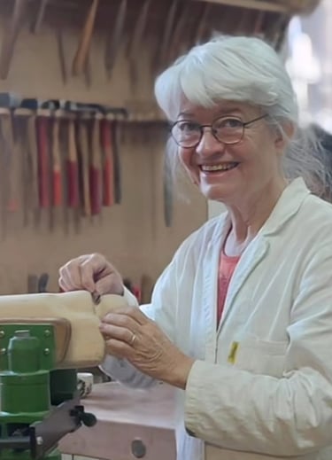 Eveline David-Valette, sculptrice sur bois, utilisant des outils manuels dans son atelier.