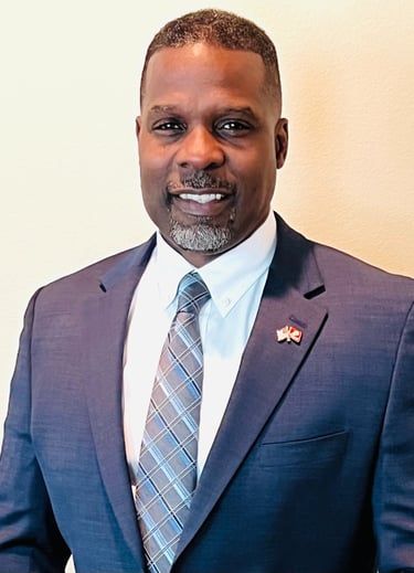 Dr. Marlon Ware professional headshot in blue suit with blue striped tie