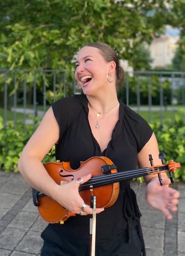 Musician Evelyn Thom holding a fiddle and smiling.