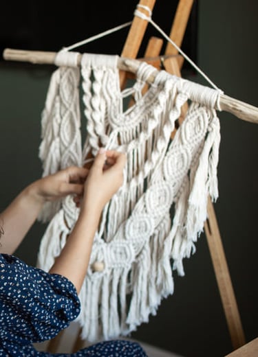 mujer sonriendo a la camara, y trabajando en un proyecto de macrame