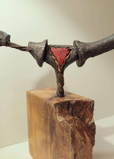 Close up of a semi circular, linear sculpture, painted bronze with red detail, on yew plinth.