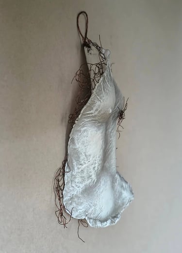 A hanging relief sculpture of a female torso with wire around it and protruding through it.