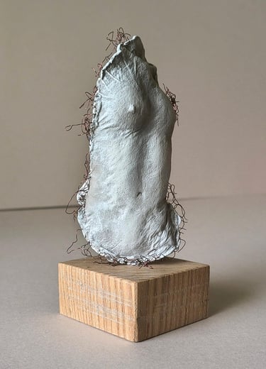 A plinth mounted sculpture of a female torso with wire around it and protruding through it.
