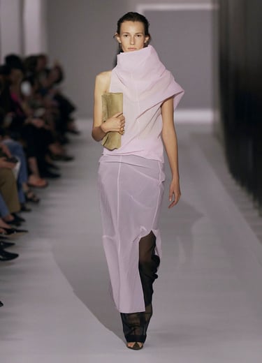 Model in a pastel draped gown with sheer layers on the Khaite runway.