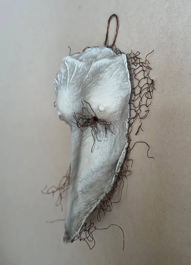 A hanging relief sculpture of a female torso with wire around it and protruding through it.