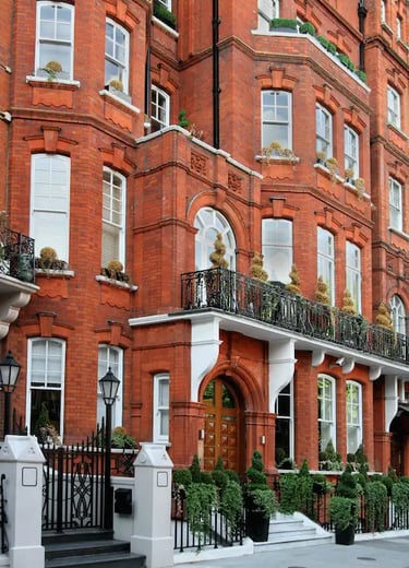 Classic London Mayfair luxury apartment building with arched windows and black iron balconies.