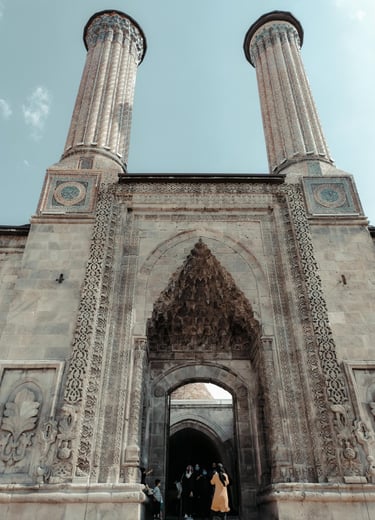 The historic Twin Minaret Madrasa in Erzurum, Turkey, featuring intricate Seljuk stonework and blue tiles.