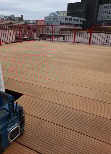 Terrasse en lames composites avec structure invisible, installation en cours sur toiture urbaine.