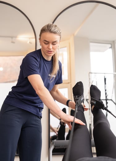 woman helping another person during pilates class