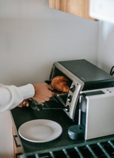 A person using a toaster oven as an energy savings alternative to using a traditional oven.