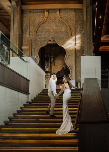 Couple walking down the grand staircase during a luxury prewedding photoshoot at Apurva Kempinski Bali
