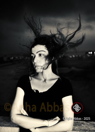 B&W photograph of a girl with the wind blowing her hair upwards. 