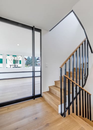 modern staircase with wood steps and black metal railing in bright hallway