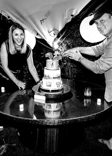 a man and woman cutting a cake with candles
