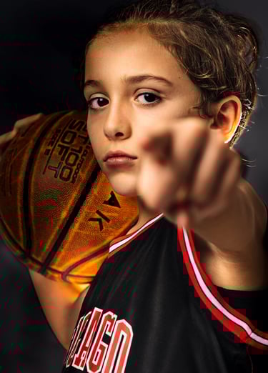 a young boy holding a basketball ball and pointing at the camera