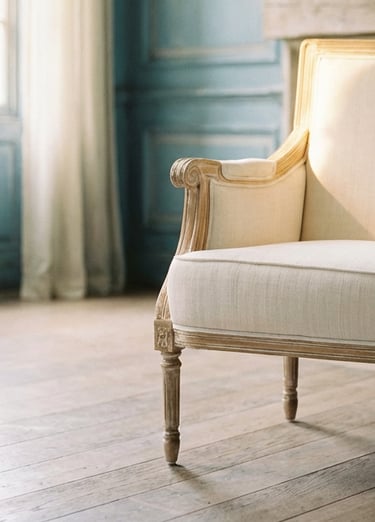 Vintage French upholstered armchair with a carved wood frame in a bright sunlit room with blue walls.